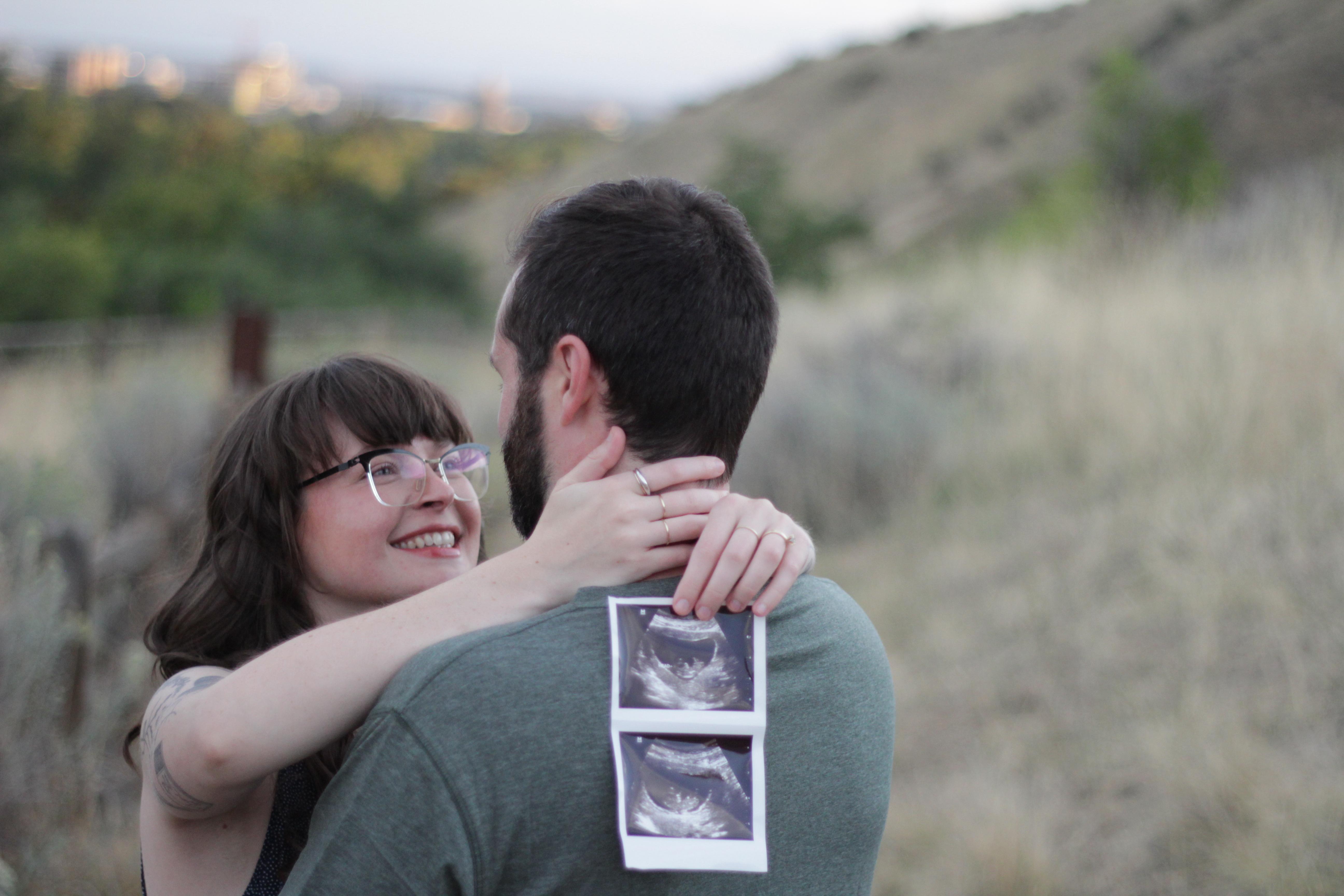 Happy couple embracing with ultrasound photos on back